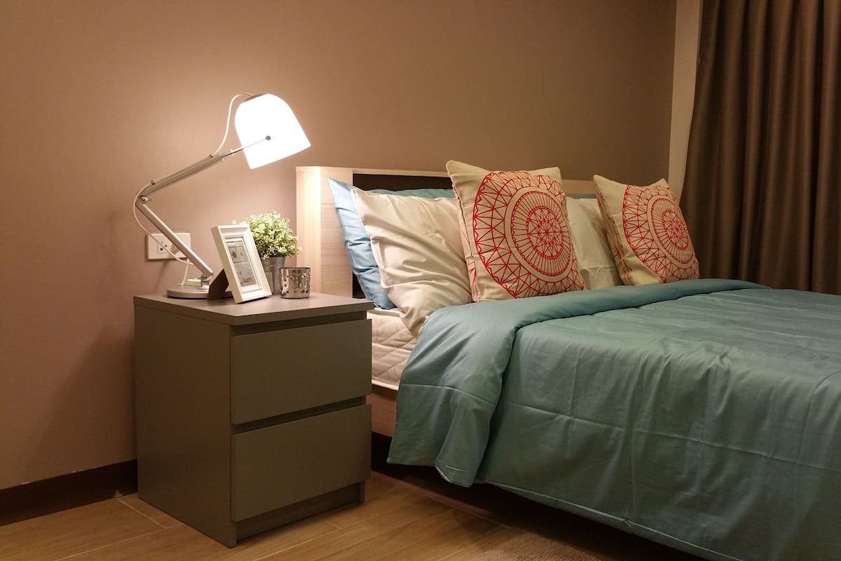 A neatly arranged bedroom with a bed, a bedside table with a lamp, and a nightstand.
