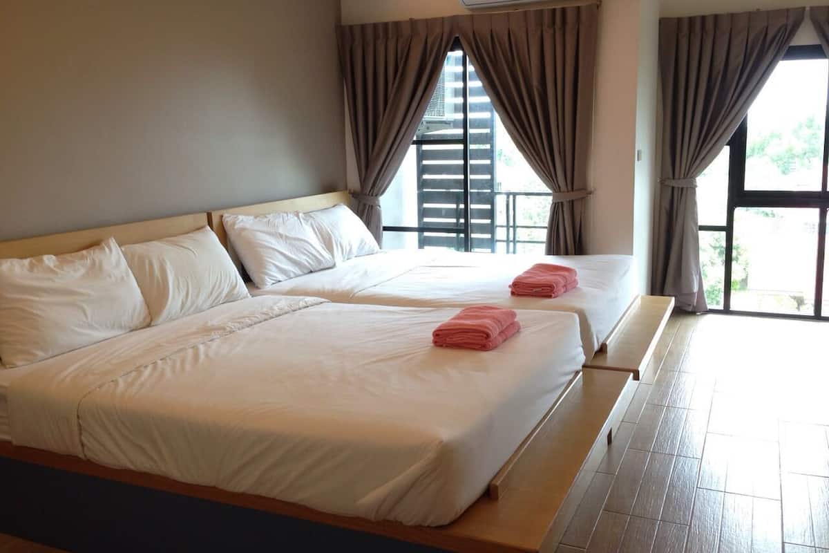 A hotel room with two beds, white linens, and a view through large windows.