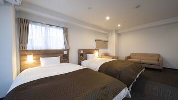 A hotel room with two beds, a sofa, a flat-screen TV, and a window with curtains.