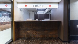 A reception desk with a brick counter, a sign above indicating 'FRONT', and a clock on the wall.