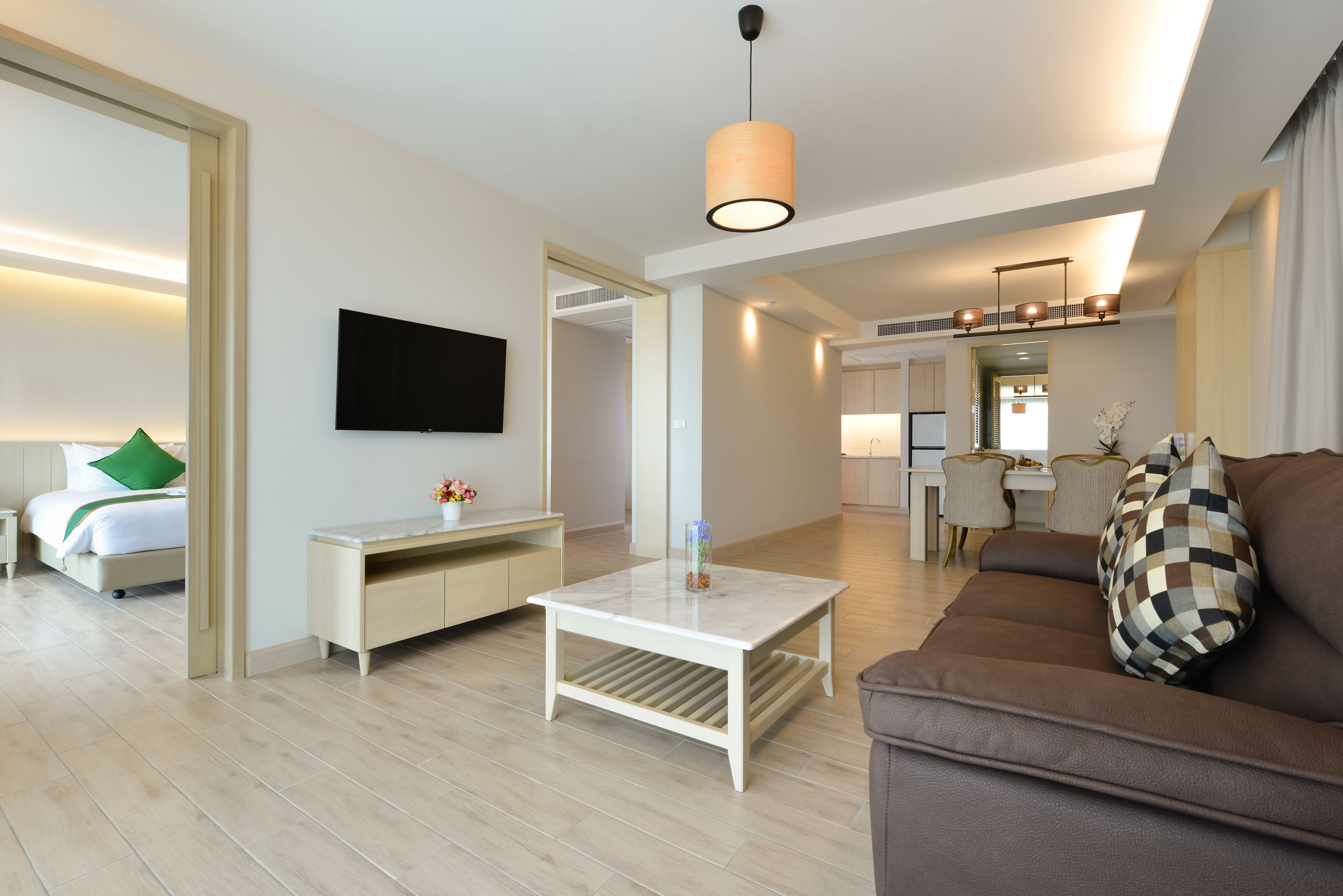 Moderni hotellihuone, jossa on sänky, sohva, sohvapöytä, televisio ja ruokailutila.