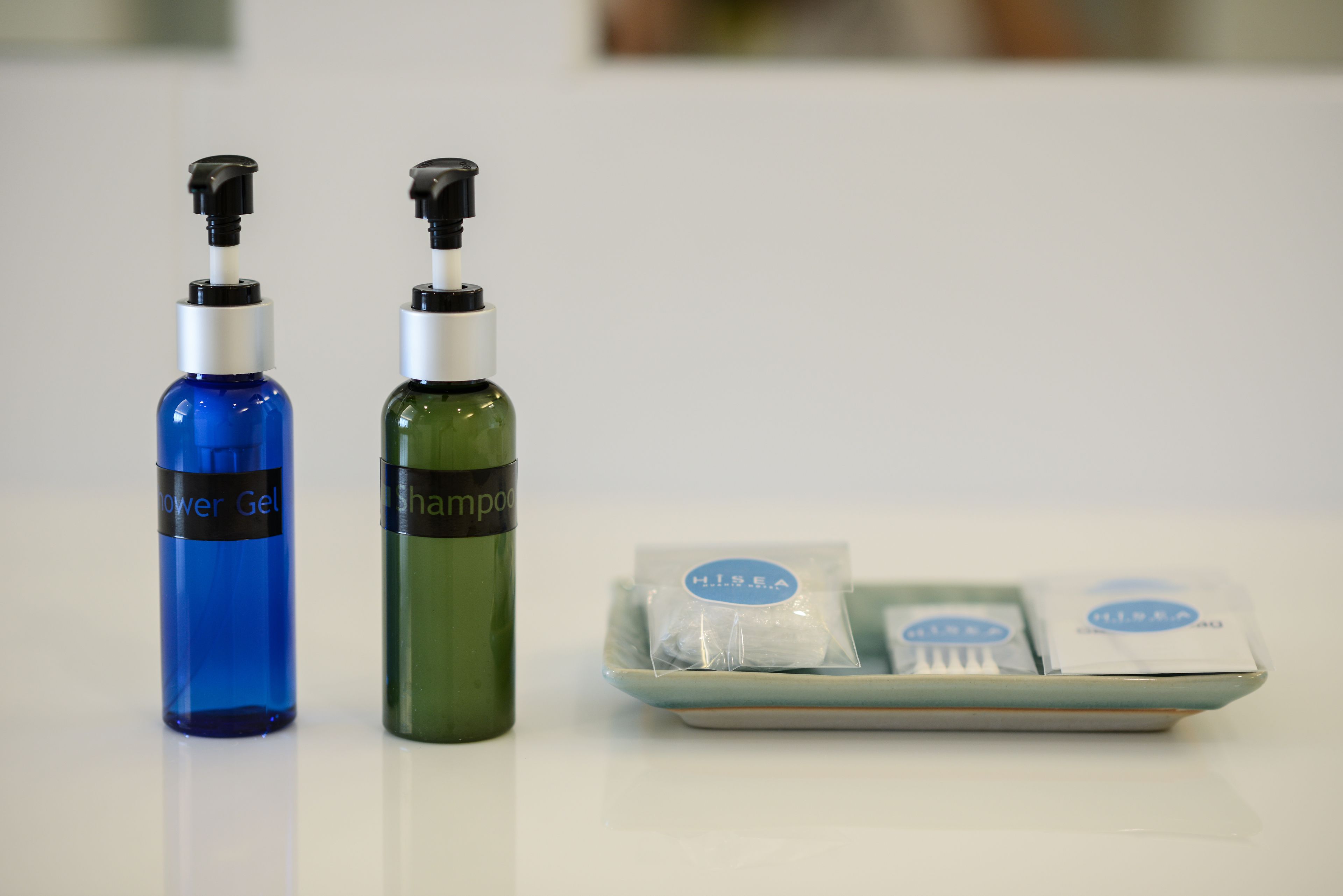 Two bottles of shower gel and shampoo, and a tray with two packets of shampoo and a toothbrush.