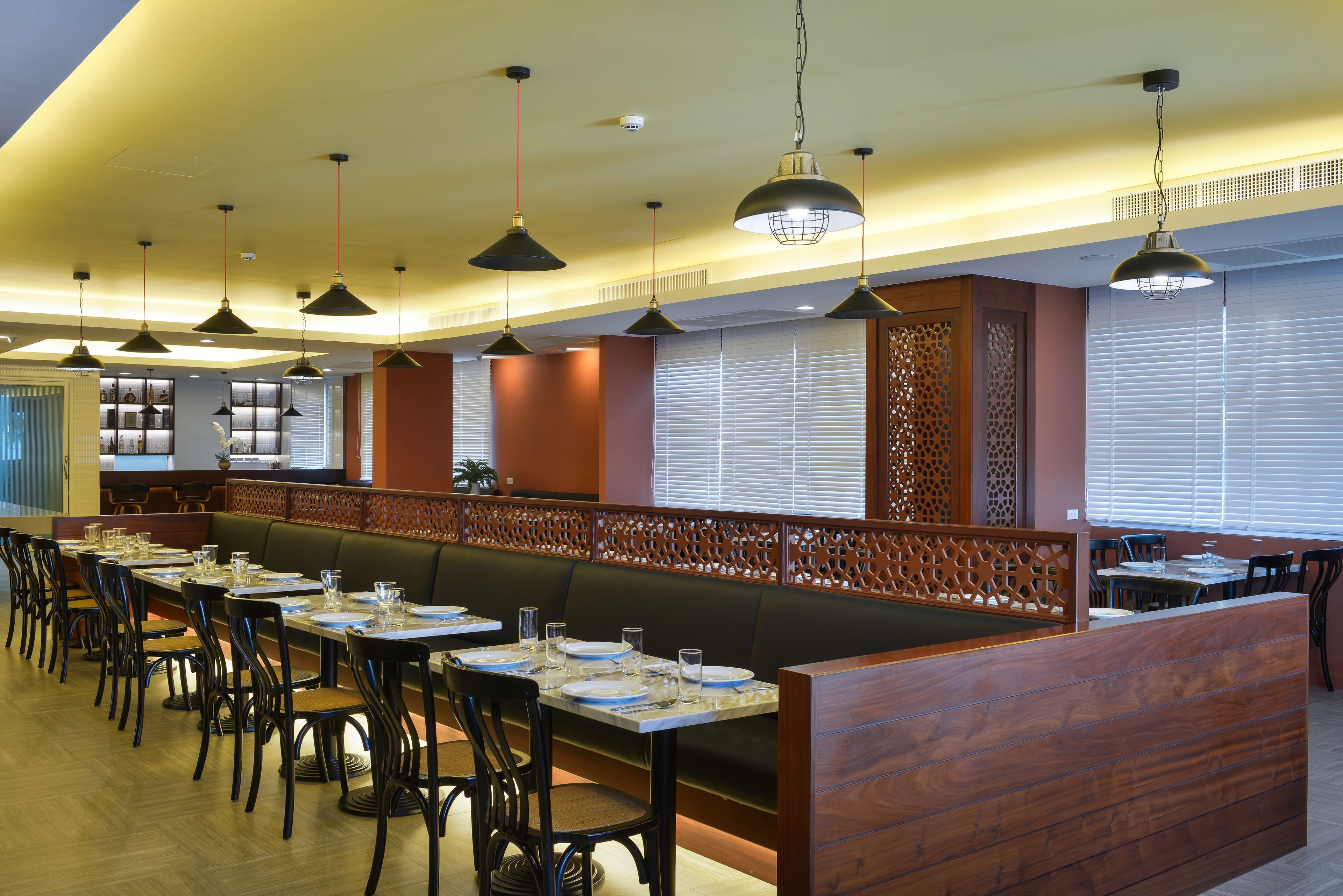 A restaurant with long communal tables, booths, and hanging pendant lights.
