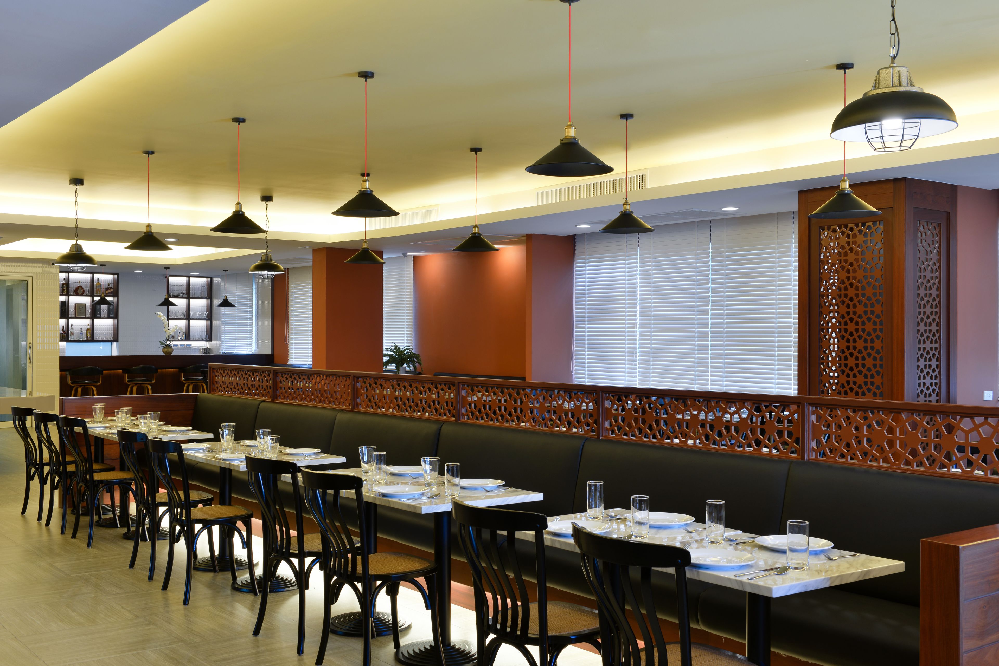 Un restaurante con mesas largas, sillas e iluminación colgante.