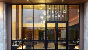 L’entrée d’un hôtel, avec de grandes portes vitrées, une enseigne indiquant « HISEA HUATIN HOTEL » et un intérieur moderne visible à travers le verre.