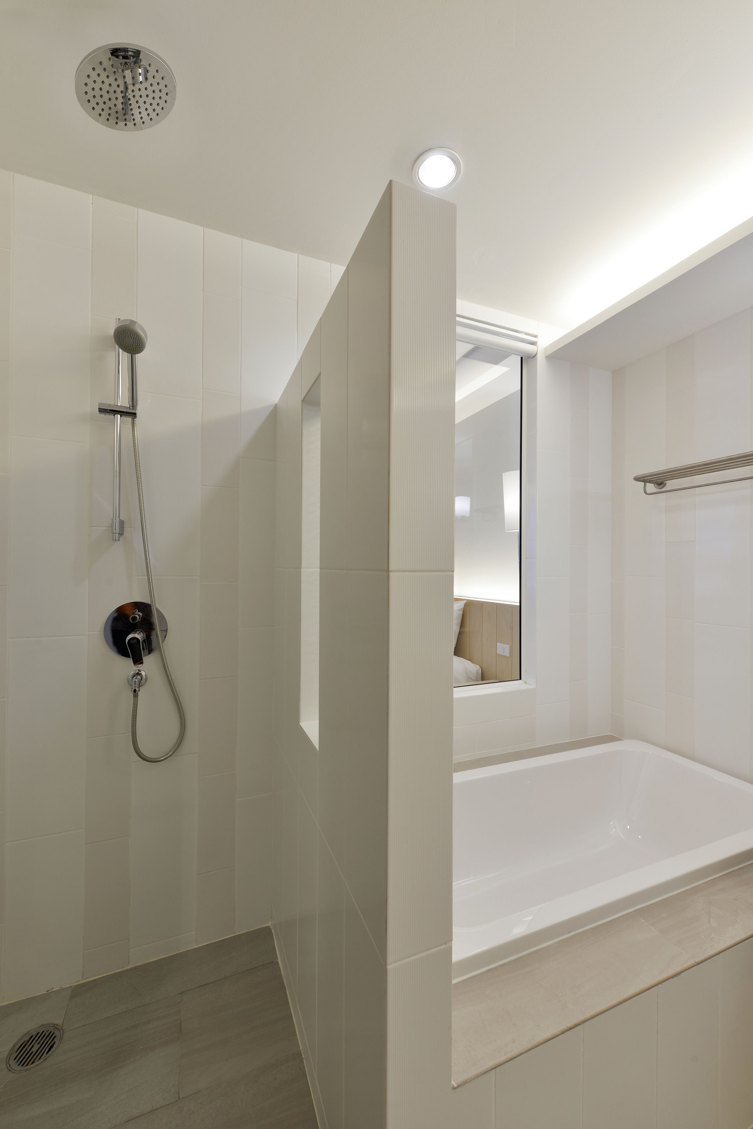 Een moderne badkamer met een douche, een bad en een spiegel.