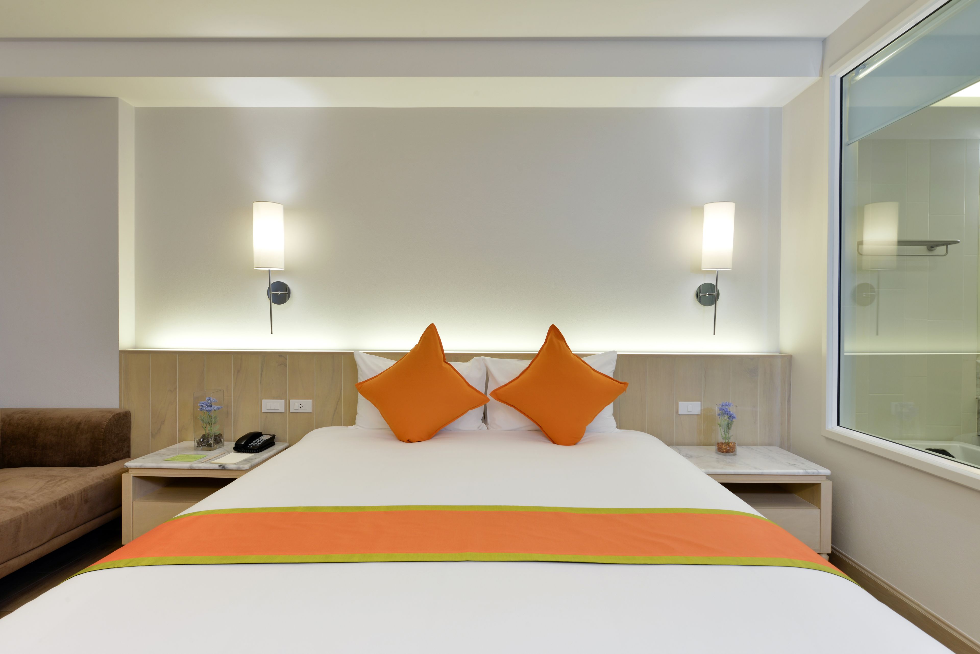 A hotel room with a large bed, two nightstands, a bedside table, a lamp, and a window.