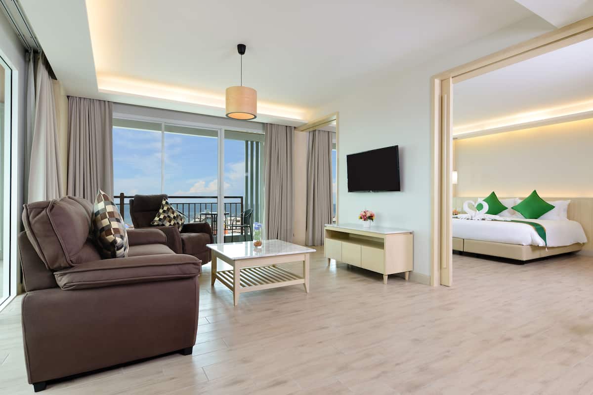 A hotel room with a sofa, a coffee table, a desk, a bed, and a TV.