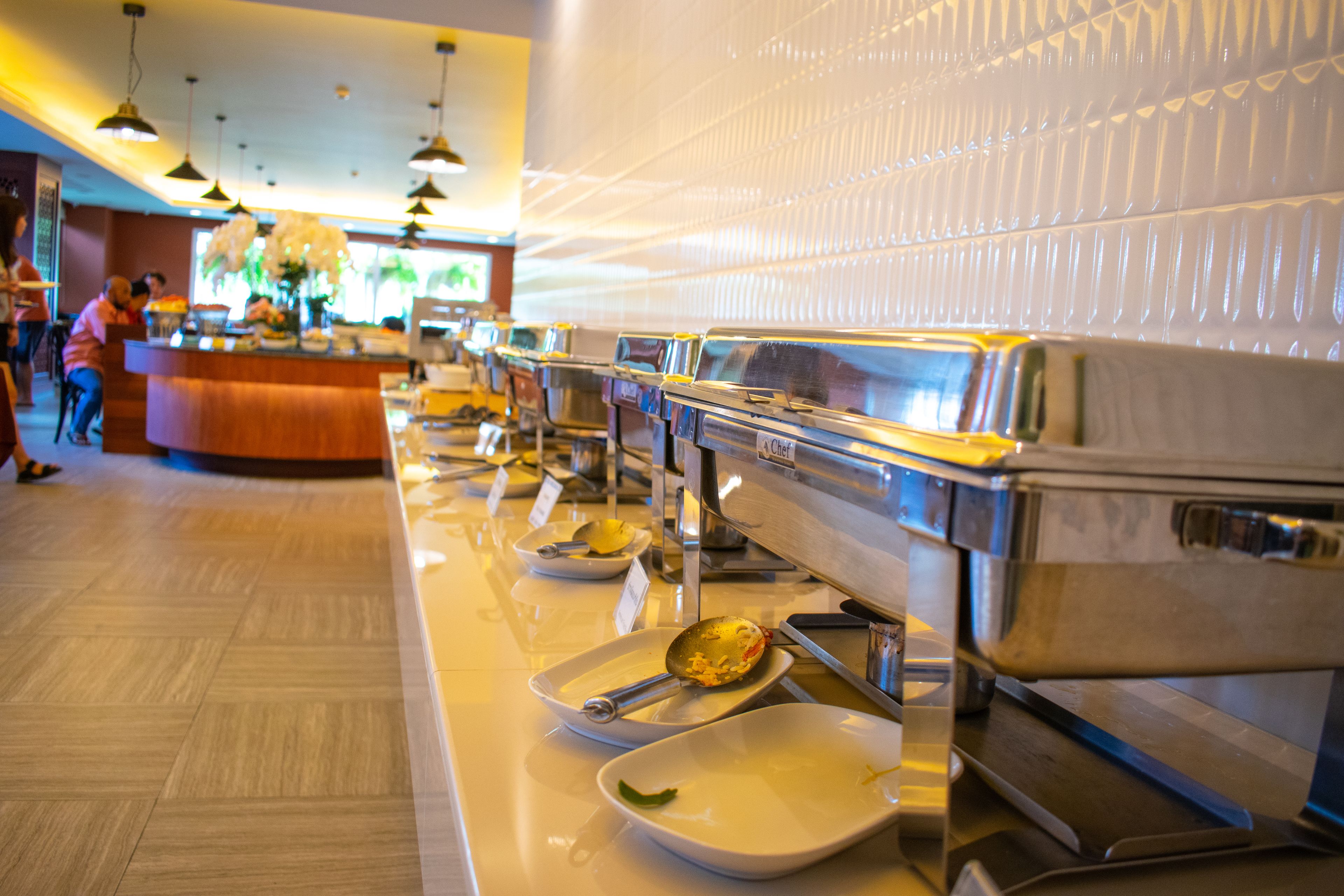 A buffet line with various dishes and utensils.