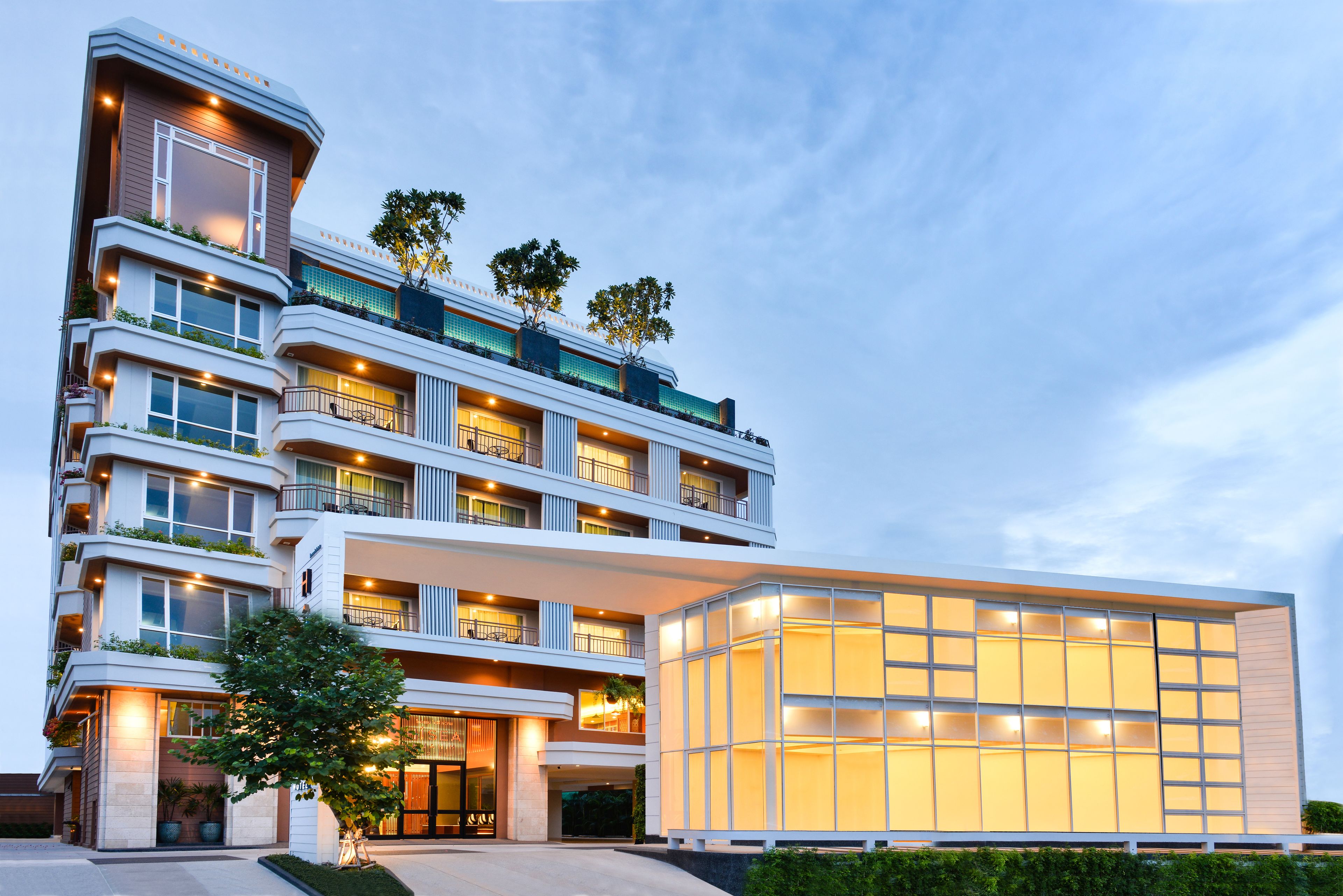 A multi-story hotel with balconies, large windows, and a well-lit entrance.