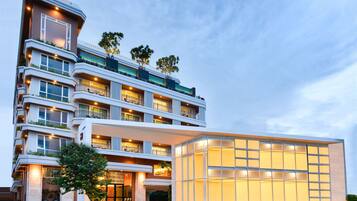 A multi-story hotel with balconies, large windows, and a well-lit entrance.