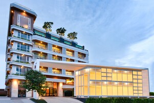 Un hotel de varios pisos con balcones, amplias ventanas y una entrada bien iluminada.