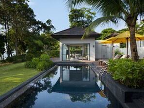 A modern house with a glass door leading to a patio area, a swimming pool, and a yellow umbrella.