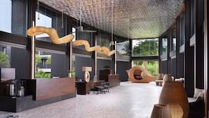 Eine geräumige Lobby mit Empfangstresen, einer Sitzecke und großen Fenstern mit Blick auf Grünflächen.