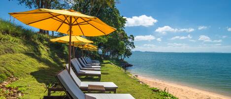 A beachside lounge area with sun loungers and yellow umbrellas.