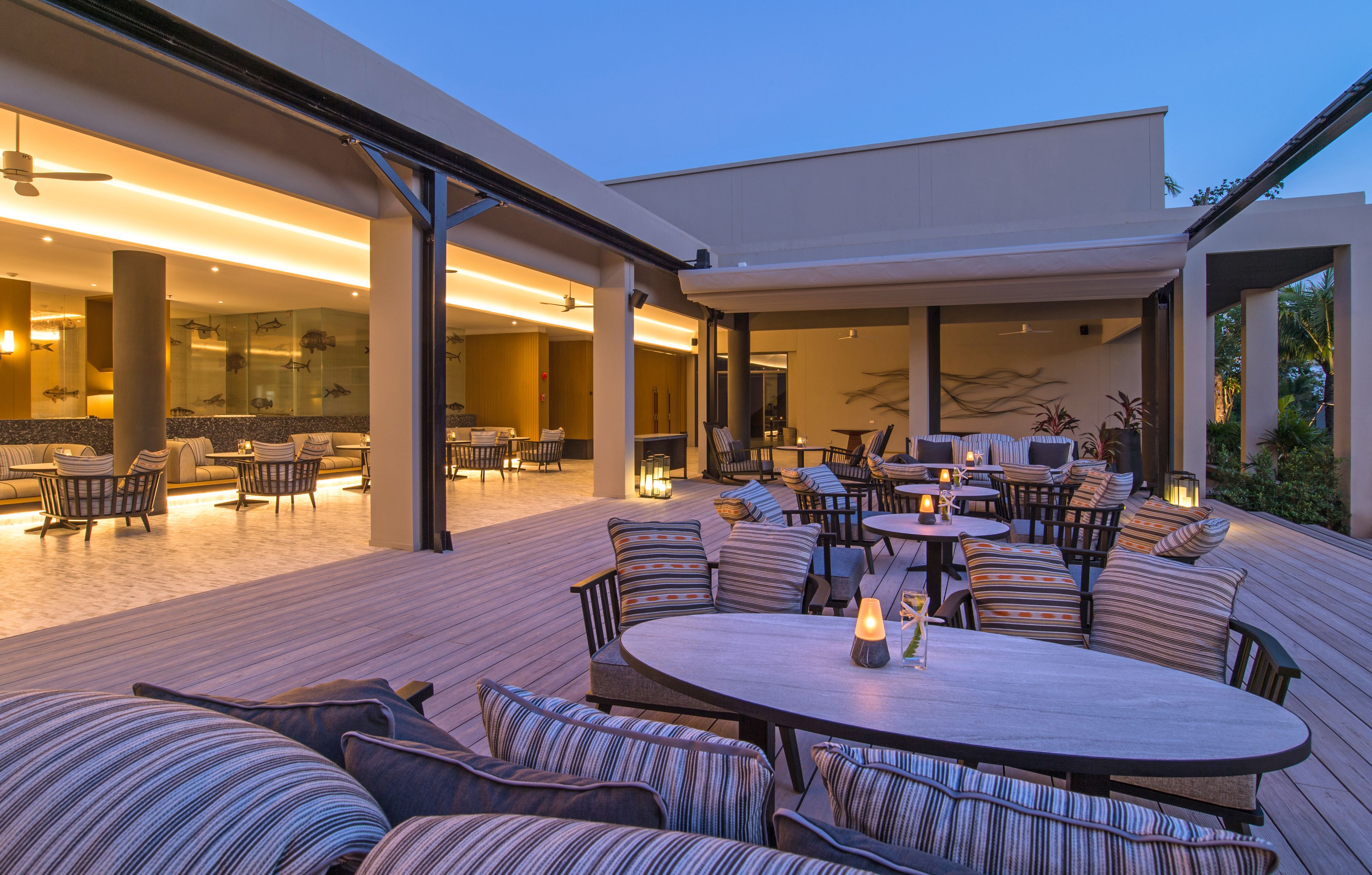 Un patio al aire libre con varios espacios de descanso, incluyendo sofás y sillones, y una mesa central con una vela.