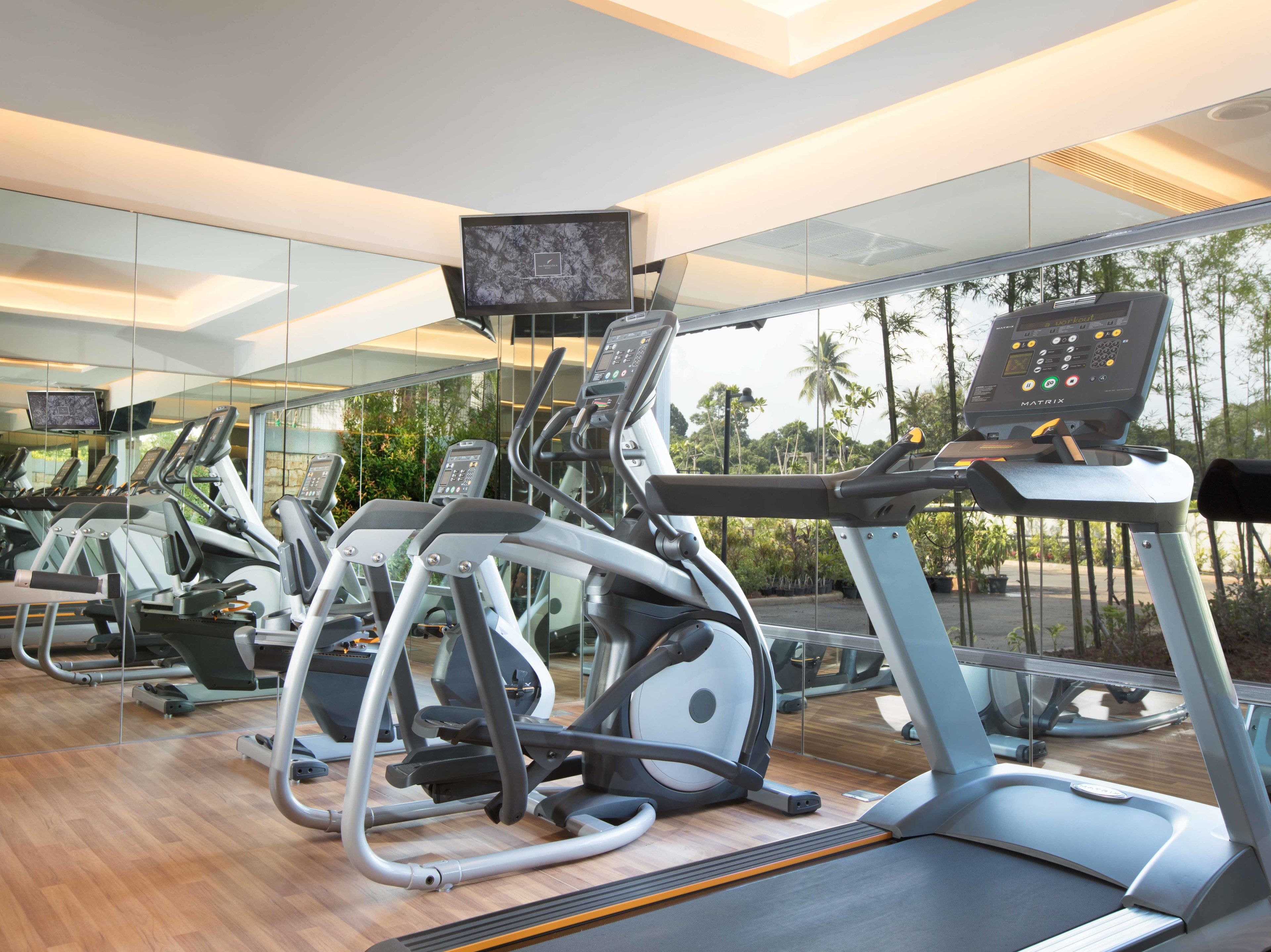 Une salle de sport équipée de plusieurs tapis de course, d’un vélo d’appartement et d’un rameur.
