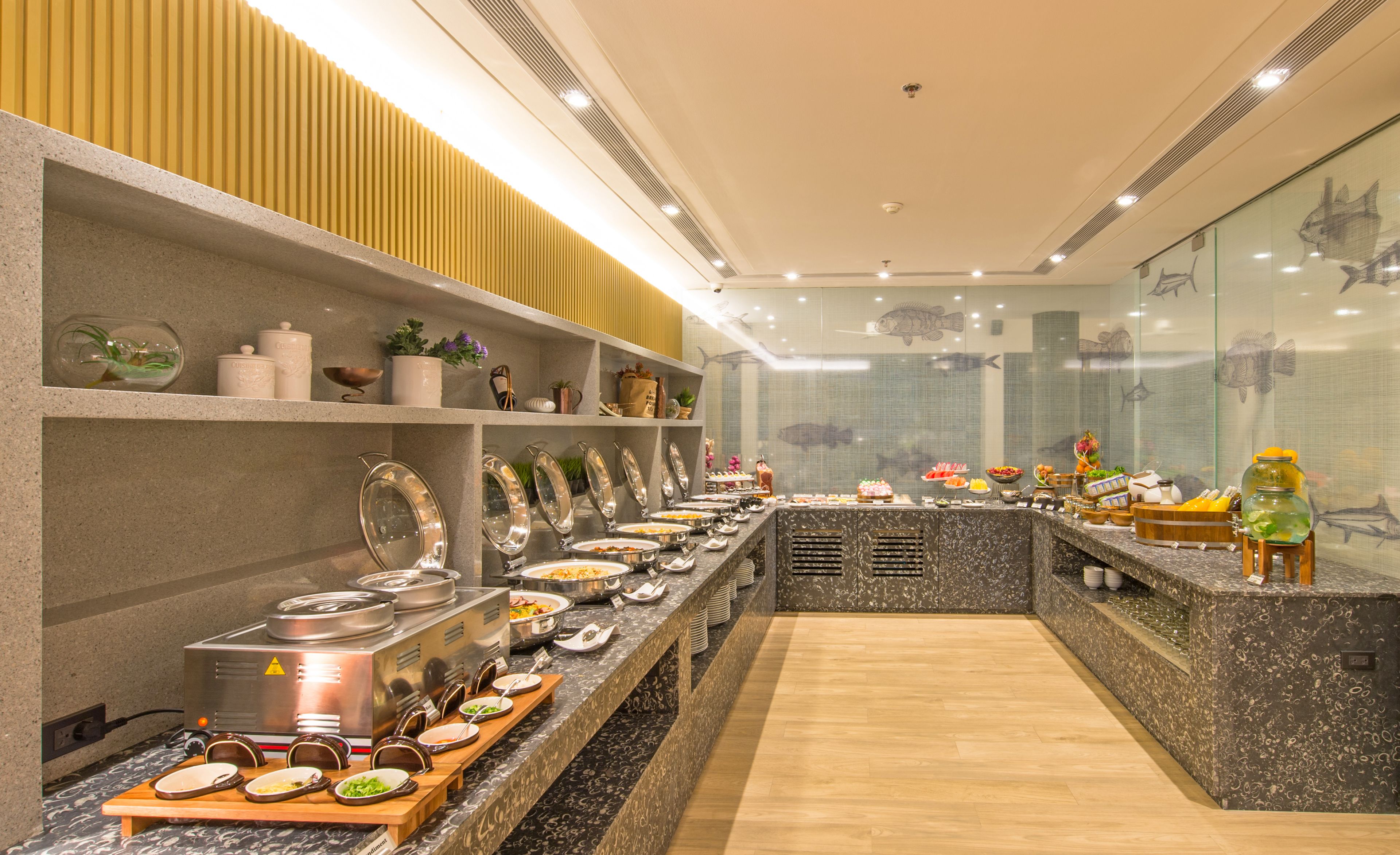 A buffet setup with various food stations and a decorative fish wall.