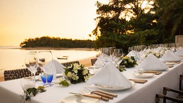 A table set for a meal with a view of the sea at sunset.