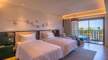 A hotel room with two beds, a small table, and a balcony with a view.