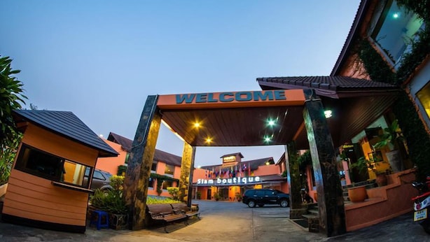 A hotel entrance with a 'WELCOME' sign, a boutique named 'Siam Boutique', and a car parked in front. - Siam Boutique (Buriram)