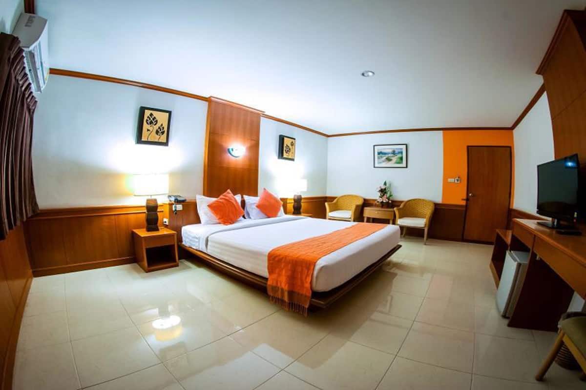 A hotel room with a bed, bedside tables, a desk, a chair, and a television.