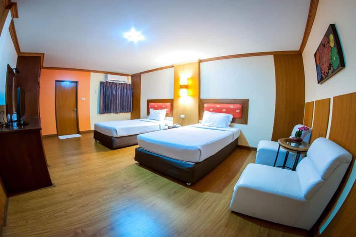 A hotel room with two beds, a desk, a chair, and a small table.