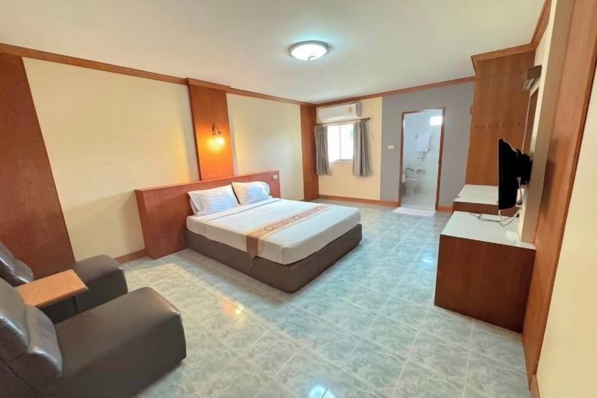 Une chambre d’hôtel avec un lit, un bureau, une chaise et un téléviseur.