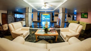 A spacious lobby with a high ceiling, a central fountain, and a seating area with two sofas and a coffee table. - Siam Boutique (Buriram)