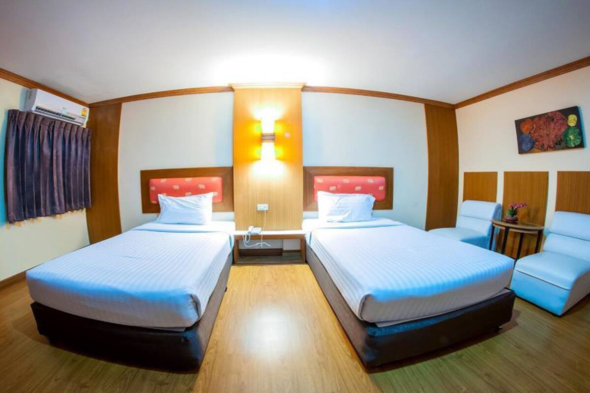 A hotel room with two beds, a desk, a chair, and a painting on the wall.