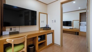 A hotel room with a wooden desk, a television, a mirror, a bed, and a wardrobe. - Nohyung Hotel (Jeju City)