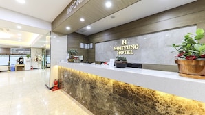 A hotel reception desk with a marble counter, a sign reading "Nohyung Hotel", and potted plants. - Nohyung Hotel (Jeju City)