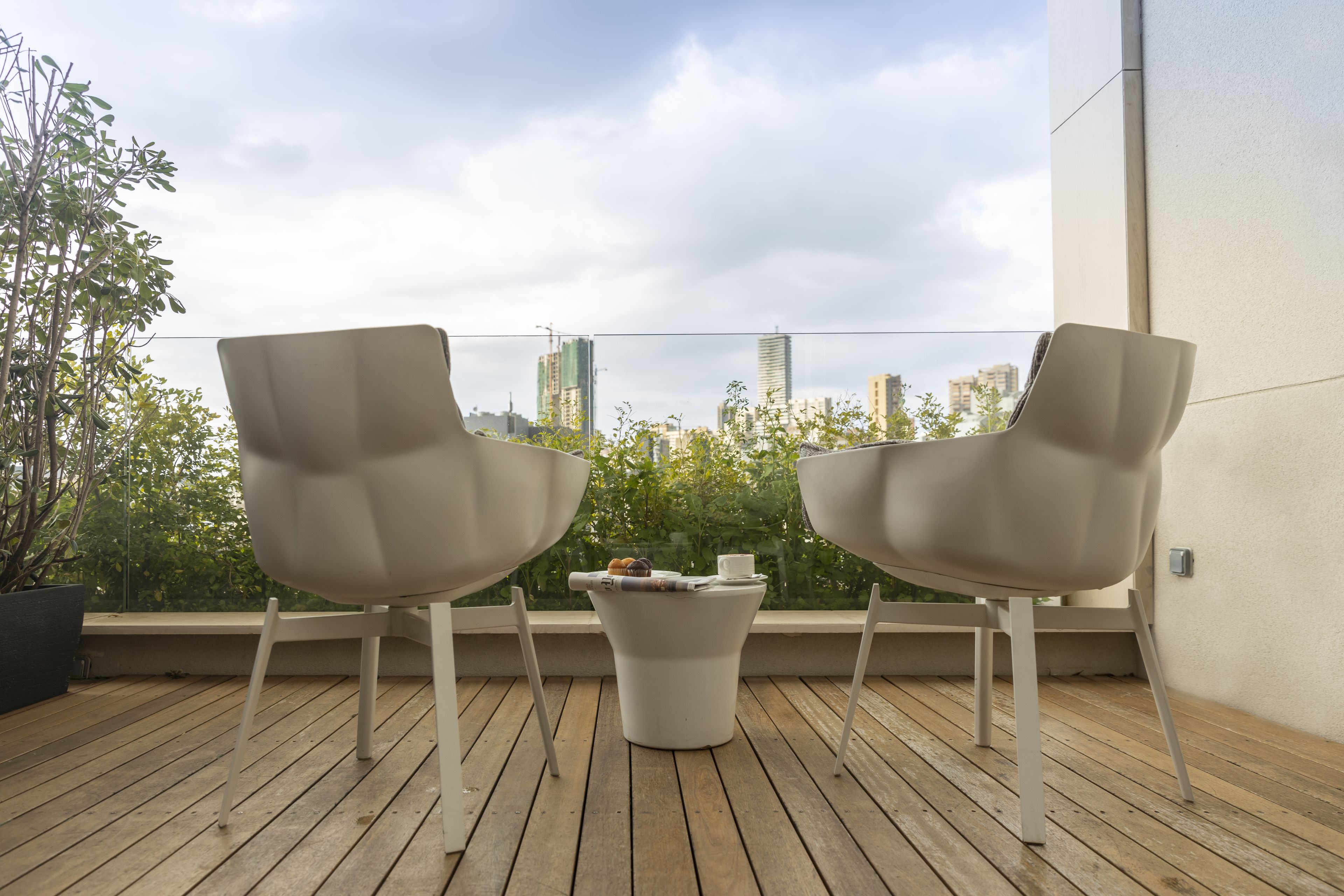 Dos sillas modernas sobre una terraza de madera con vista al horizonte de una ciudad.