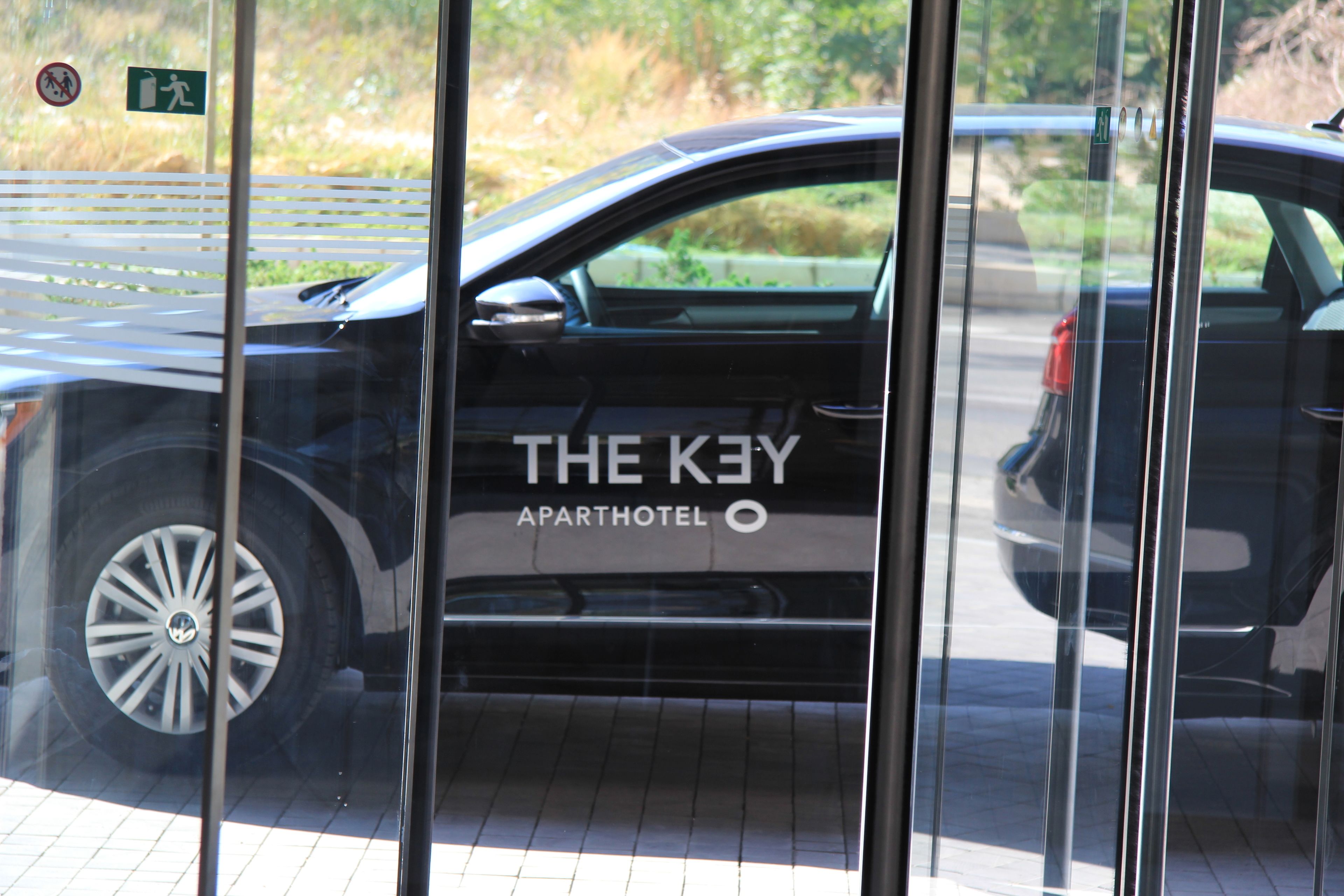 A black car with "THE KEY APARTHOTEL" on its side parked in front of a building.