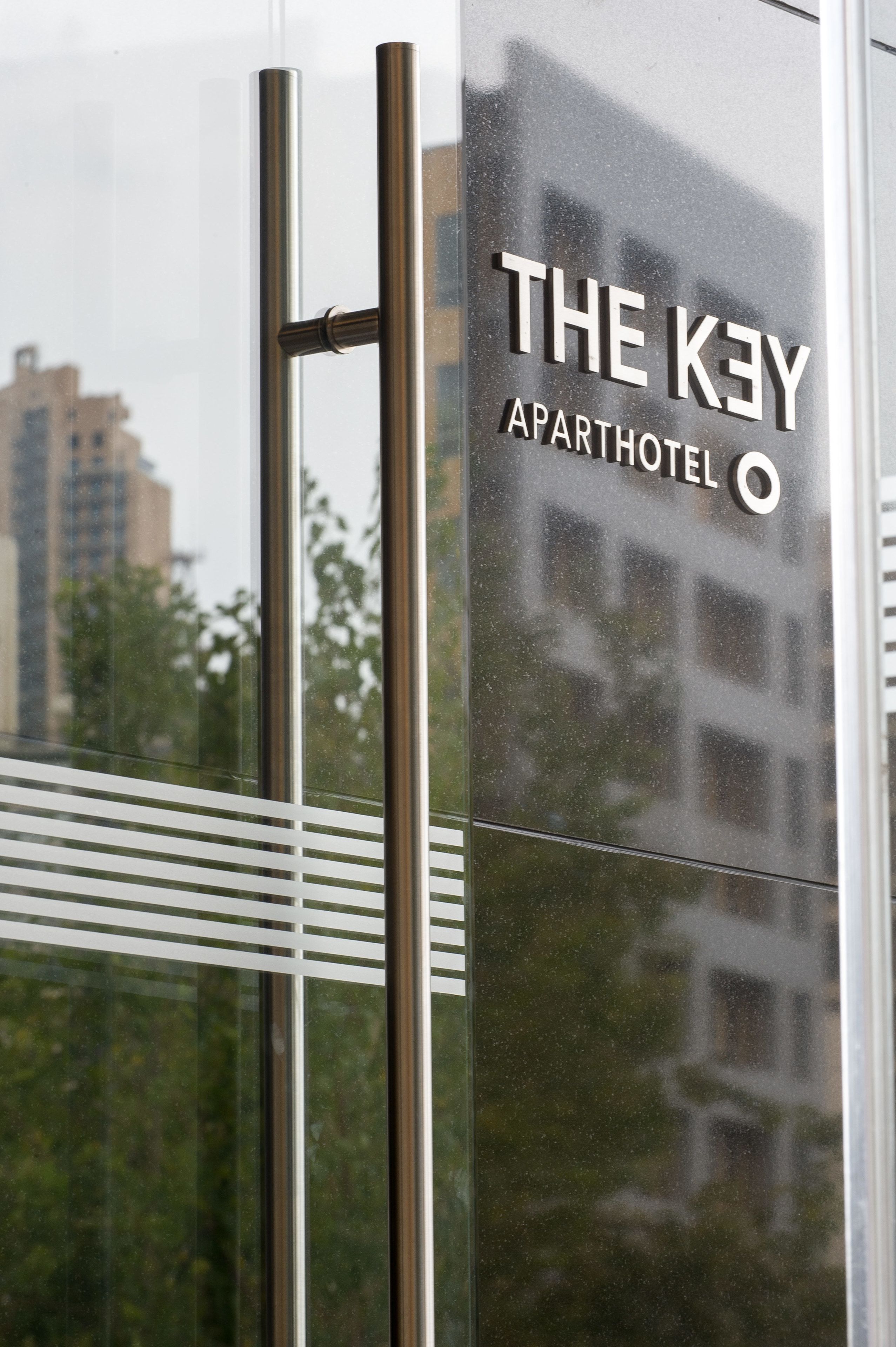 A modern building with a sign reading "THE KEY APARTHOTEL".