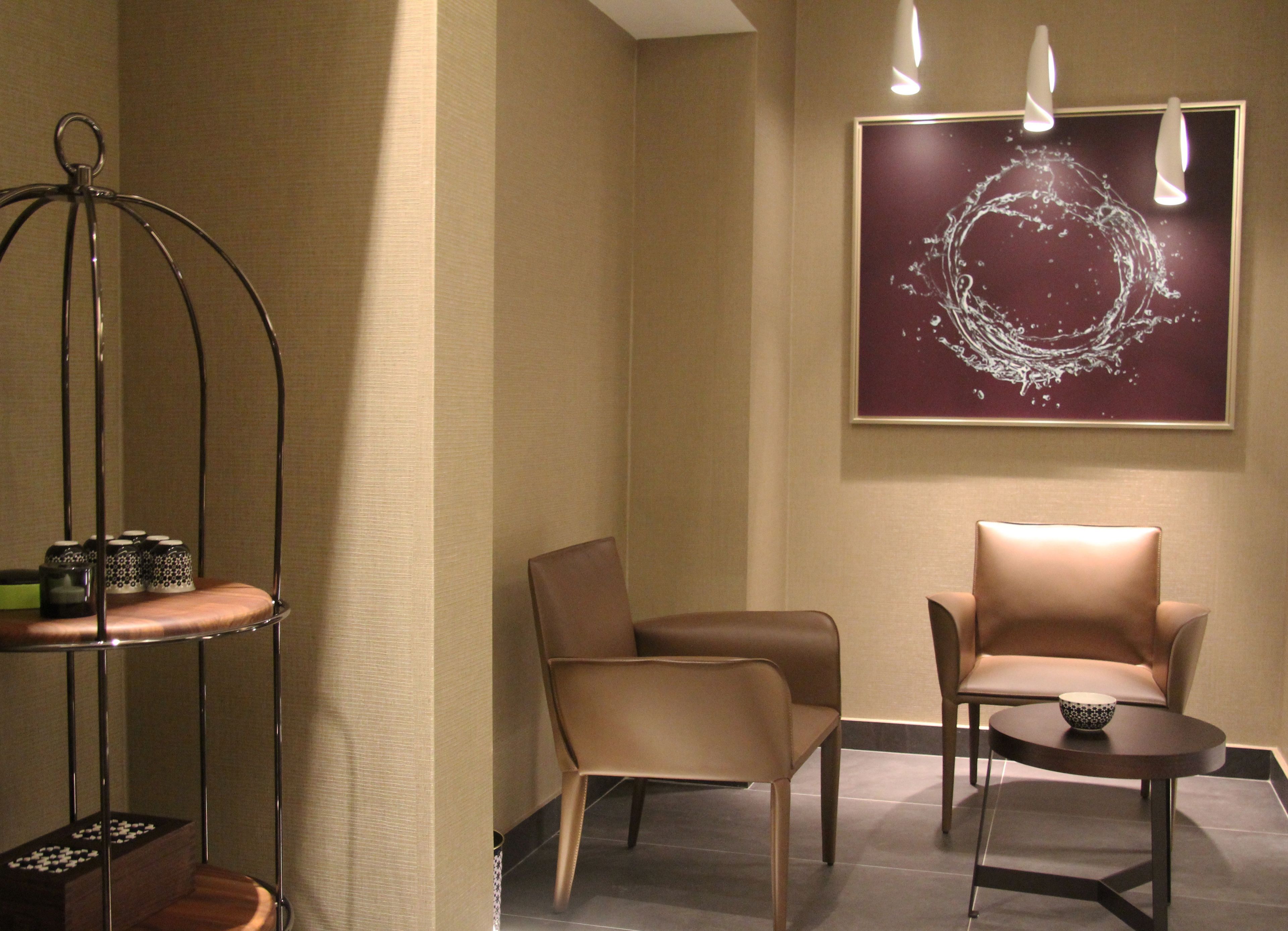 A modern room with two leather chairs, a small table, and a decorative metal stand with items on it.