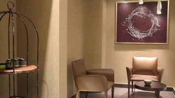 A modern room with two leather chairs, a small table, and a decorative metal stand with items on it.