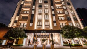 Un edificio de gran altura con varios pisos, una entrada bien iluminada y un letrero que dice "THE KEY APARTMENT HOTEL".