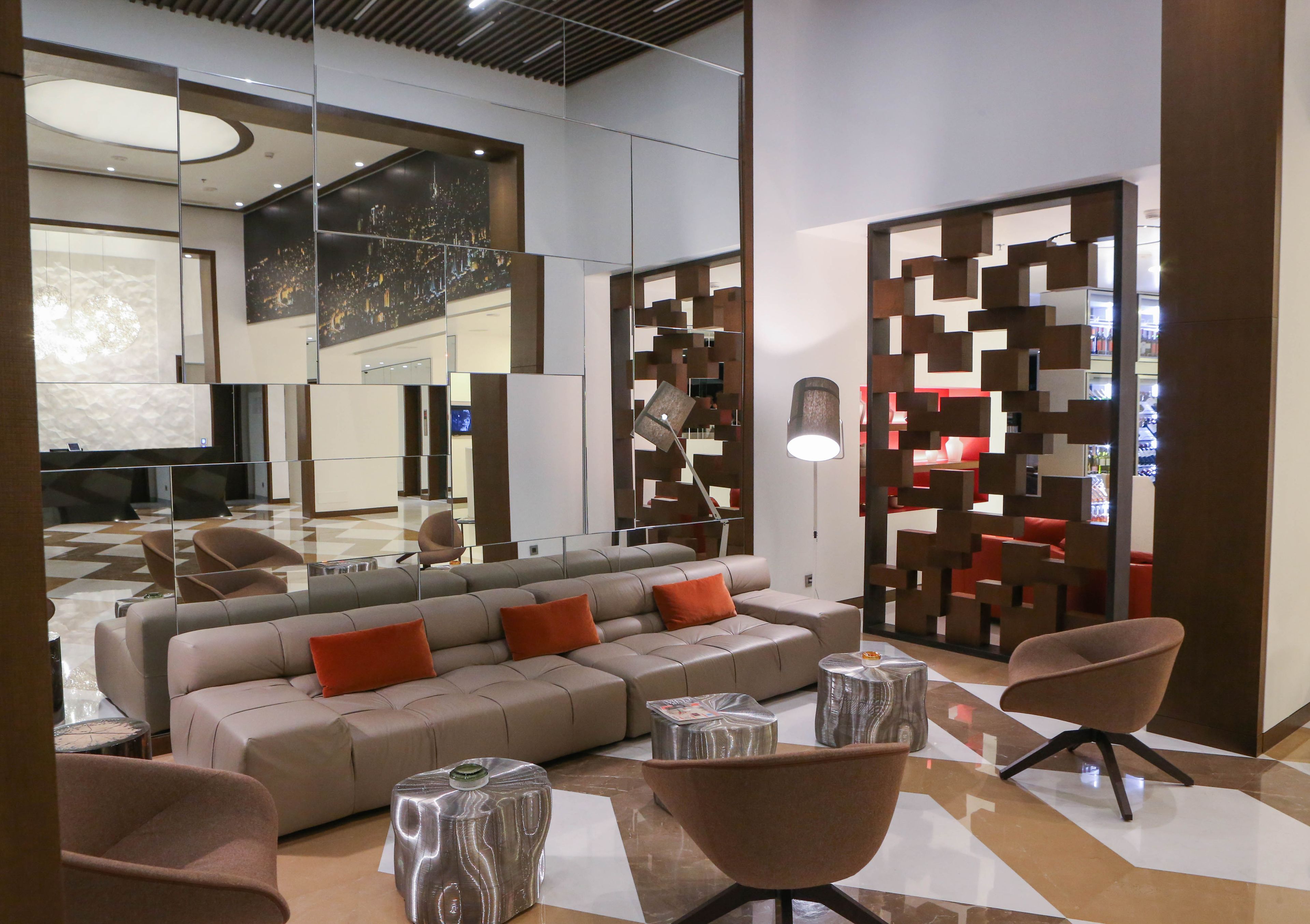 Un área de descanso moderna con un sofá modular, sillones y una mesa de centro.