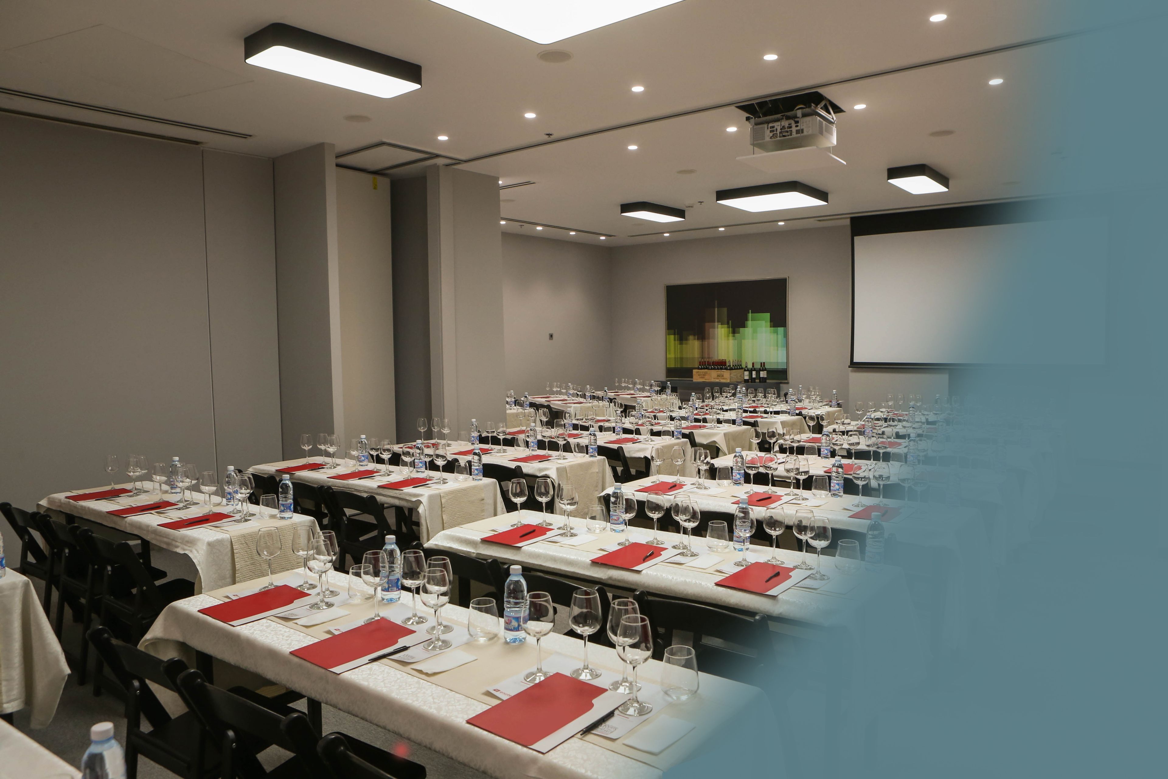 A conference room with multiple tables set for a meeting, equipped with water bottles and glasses.