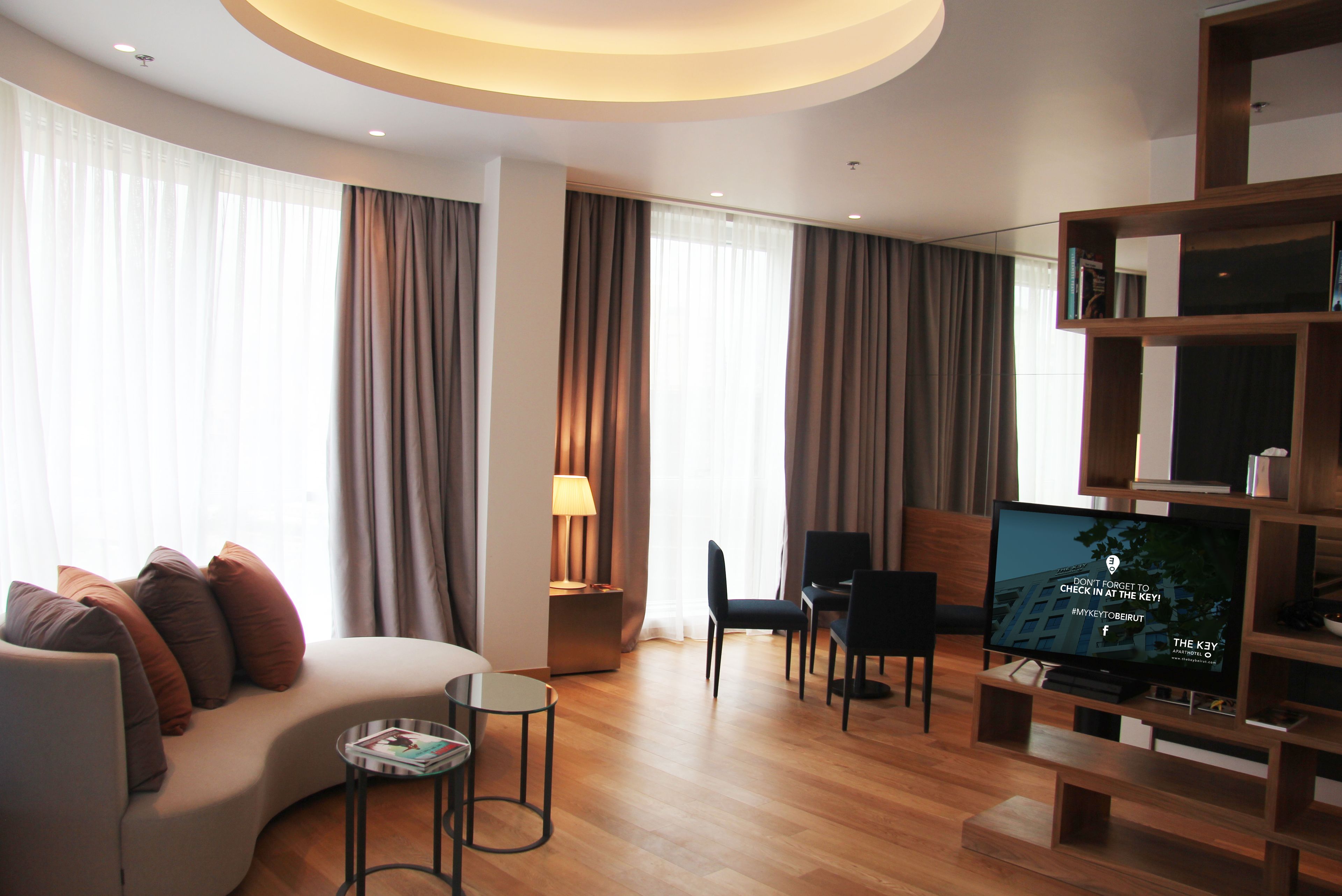 Una sala de estar moderna con un sofá curvo, un televisor y un mueble de entretenimiento de madera.