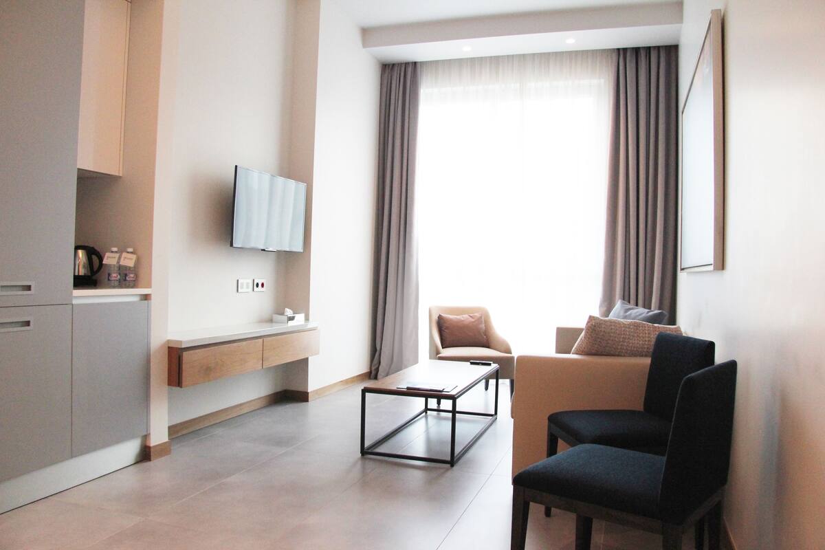 A modern living room with a sofa, a coffee table, and a TV mounted on the wall.