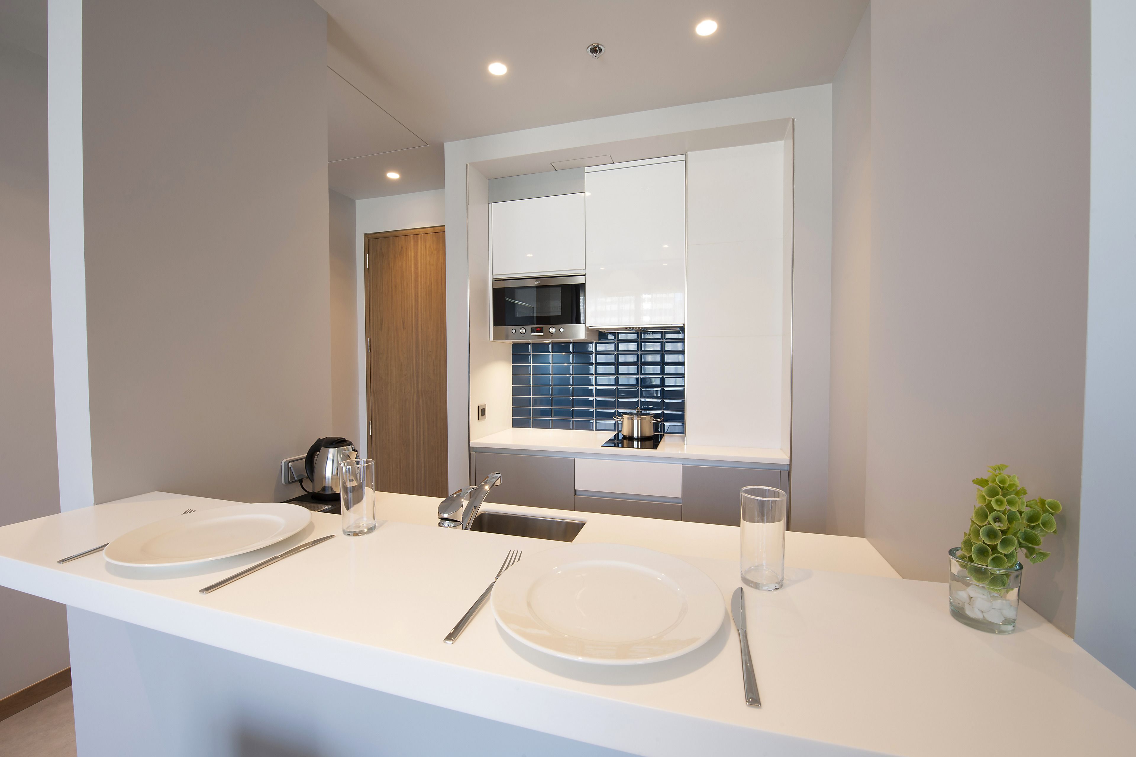 A modern kitchen with white countertops, a double sink, and a built-in oven.