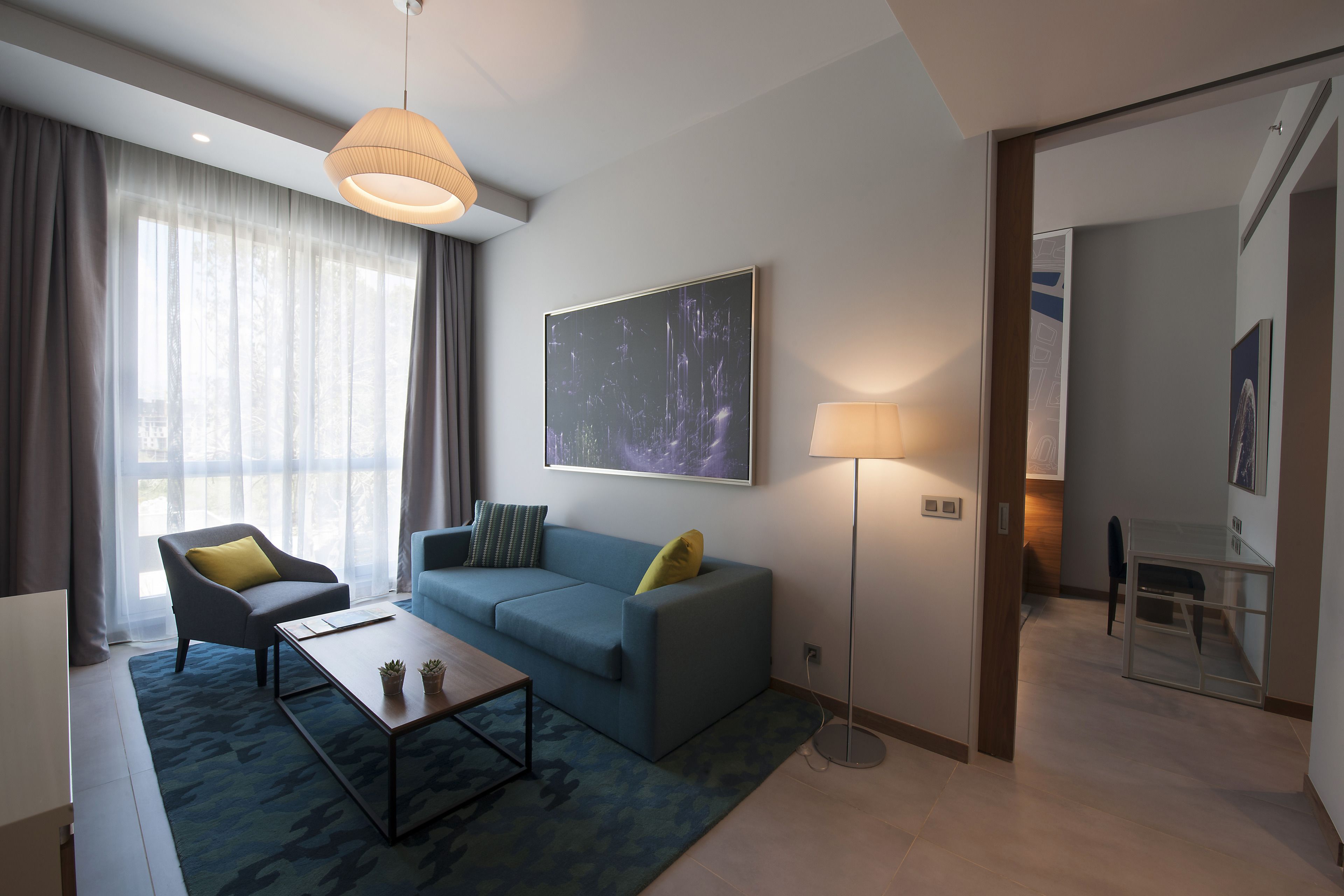 A modern living room with a blue sofa, two armchairs, a coffee table, and a floor lamp.