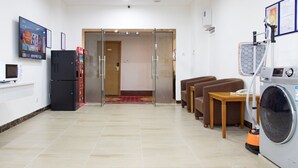 A hotel room with a flat-screen TV, a refrigerator, a washing machine, and a sofa. - Nan Fang Da Sha Hotel (Guangzhou)