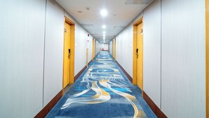A long, narrow hotel corridor with a patterned carpet, doors on both sides, and a bright ceiling light. - Nan Fang Da Sha Hotel (Guangzhou)