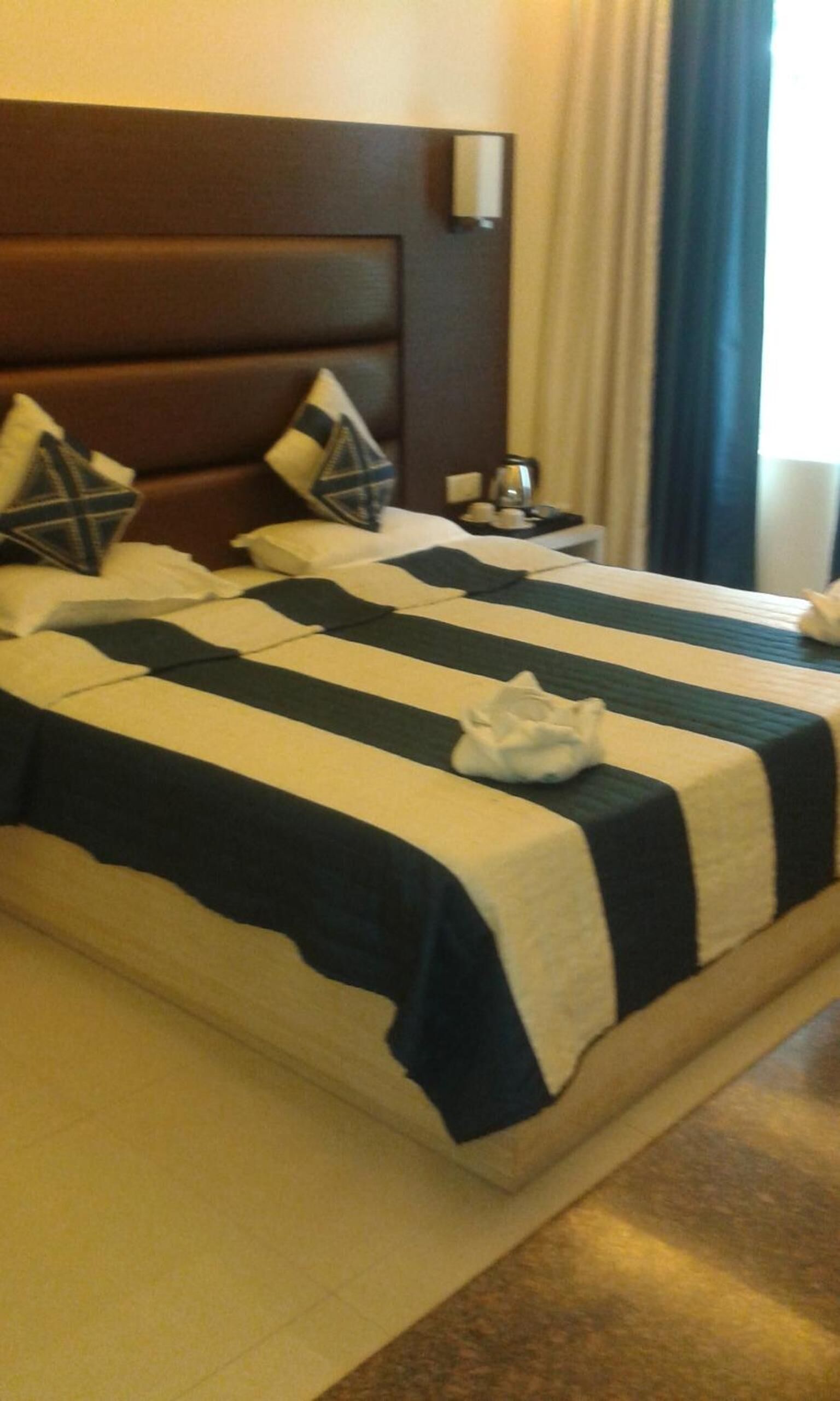 Een hotelkamer met twee bedden, elk voorzien van streepjesbeddengoed en kussens.