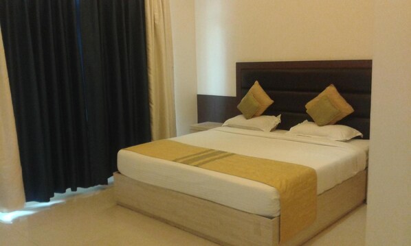 Una habitación de hotel con cama, cortinas y mesita de noche.