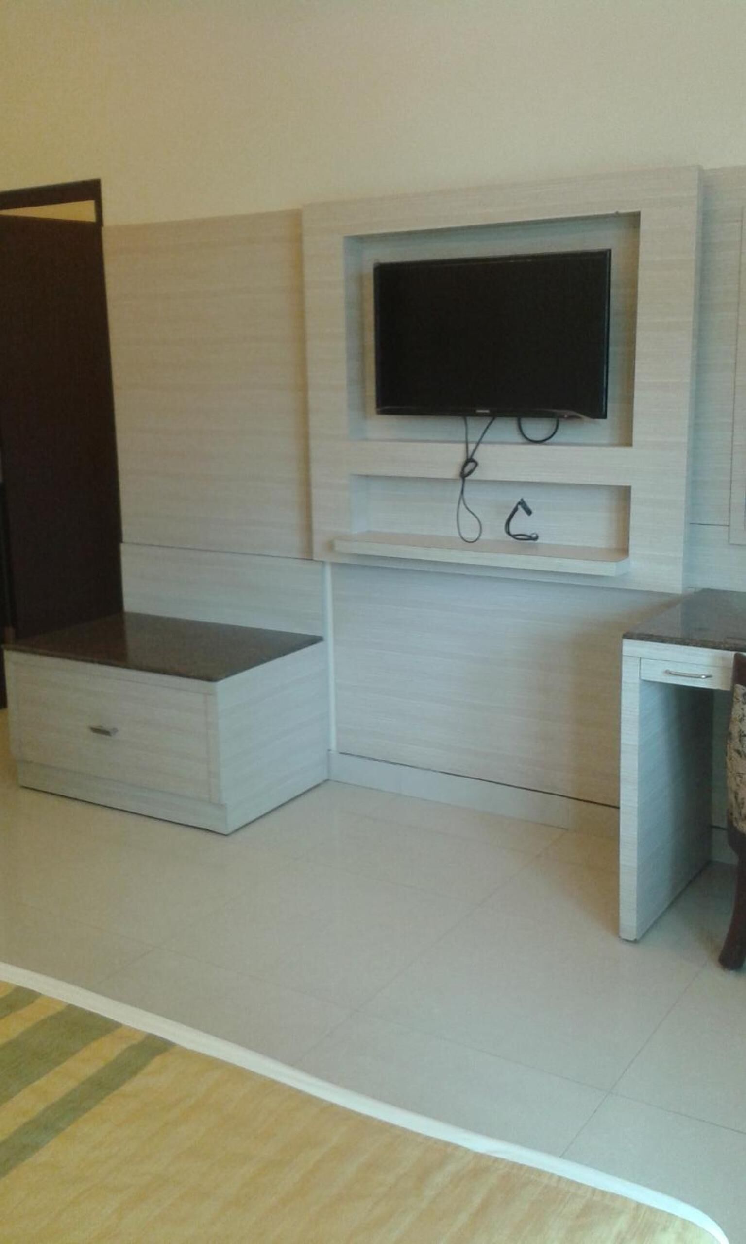 Quarto com televisão integrada, um pequeno armário e um aparador de madeira.