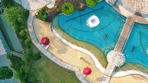 An aerial view of a landscaped area with a pool, a bridge, and surrounding greenery.